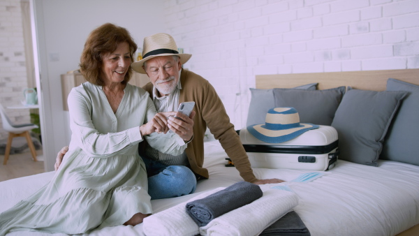 Ah appy senior couple with smartphone in hotel room, taking video.