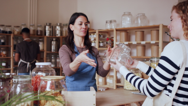 Young woman with curly hair buying fresh pasta in zero waste shop.