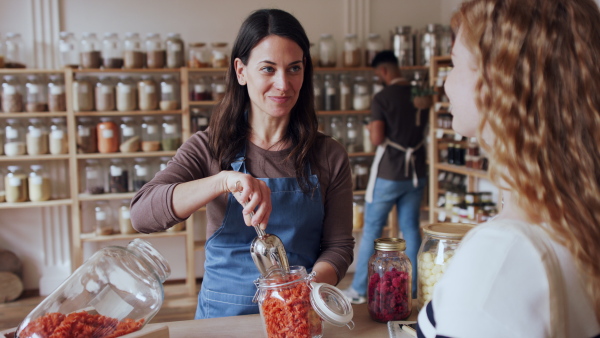 Young woman with curly hair buying fresh pasta in zero waste shop.