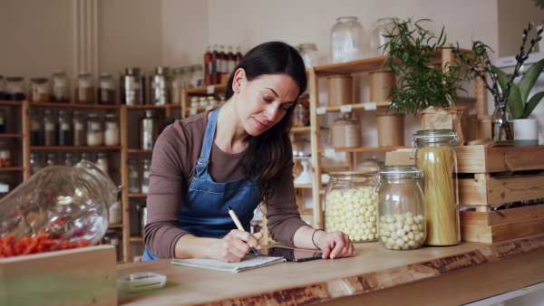 Beautiful female owner of zero waste shop doing audit.