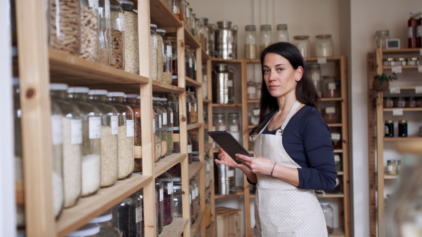 Young female owner of zero waste shop doing audit, looking at camera. Coronavirus concept.