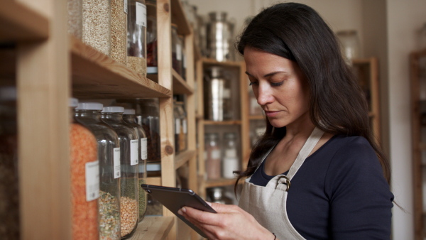 Young female owner of zero waste shop doing audit.