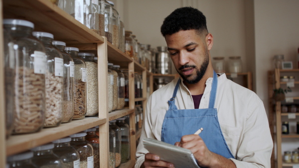 Young male owner of zero waste shop doing audit.