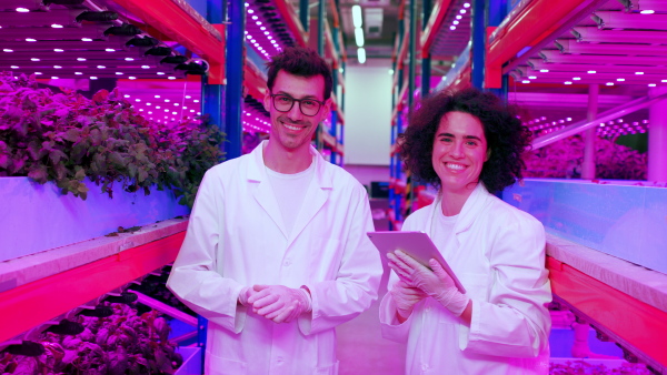 Portrait of workers using tablet on aquaponic farm, looking at camera. Sustainable business and artificial lighting.