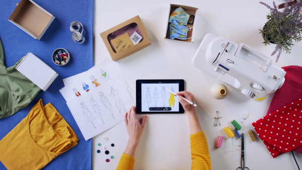 A top view of woman designing dresses on tablet, coronavirus desktop concept.