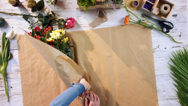 A top view of woman finishing a bouquet, giving it to customer.