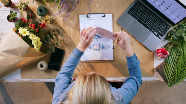 A top view of woman completing an order of flowers.