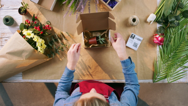 A top view of woman completing an order of flowers.