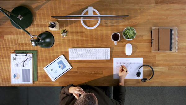 A top view of businessman working on computer at desk in home office.