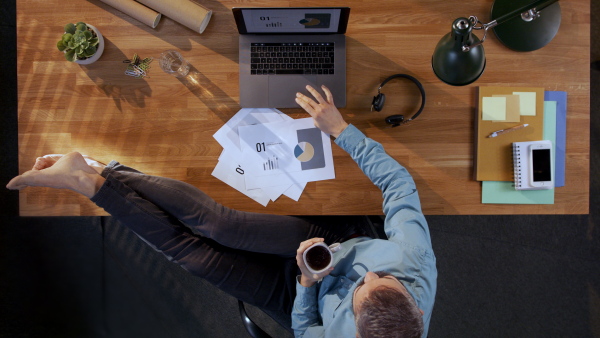 A top view of businessman working on computer at desk in home office.