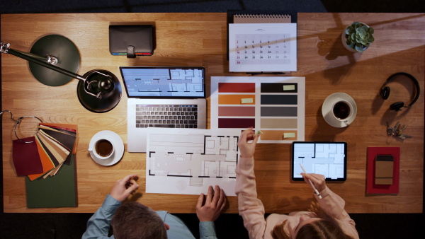 A top view of architects working on computer and tablet at desk in home office.