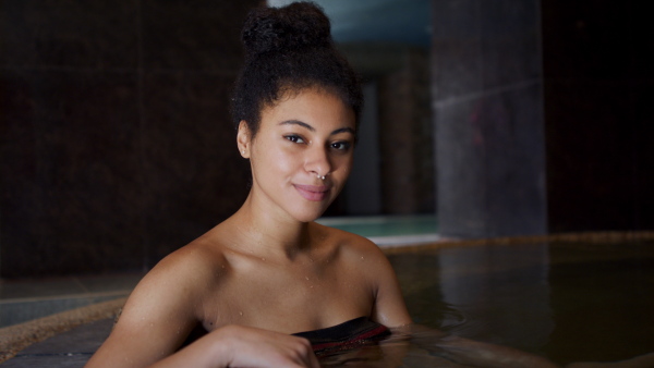 Portrait of happy young woman in indoor swimming pool, looking at camera.