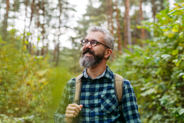 Handsome man standing in the middle of nature, enjoying peaceful atmosphere of forest, forestbathing.