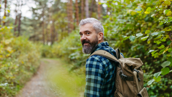 Handsome man standing in the middle of nature, enjoying peaceful atmosphere of forest, forestbathing. Banner with copy space.