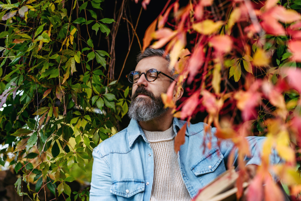 Man is enjoying relaxing, peaceful moment at home, sitting among greenery and reading a book.