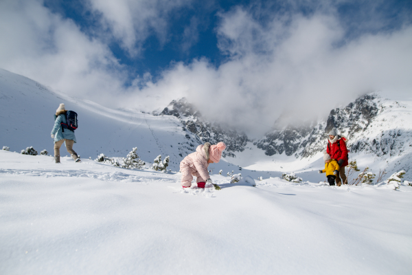 Family is enjoying winter holiday in the mountains, playing and walking through the snowy landscape.