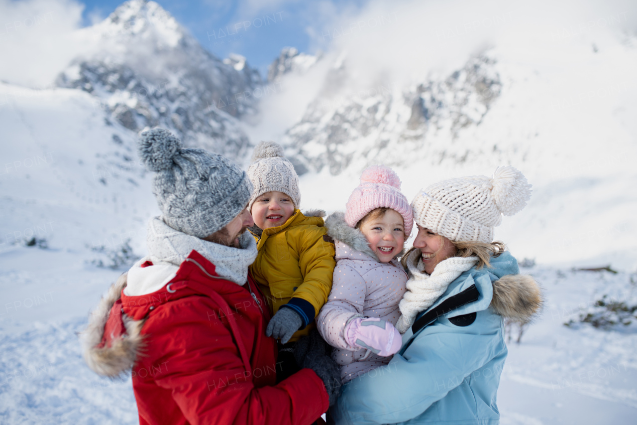 Family is enjoying winter holiday in the mountains, standing in the middle of snowy landscape.