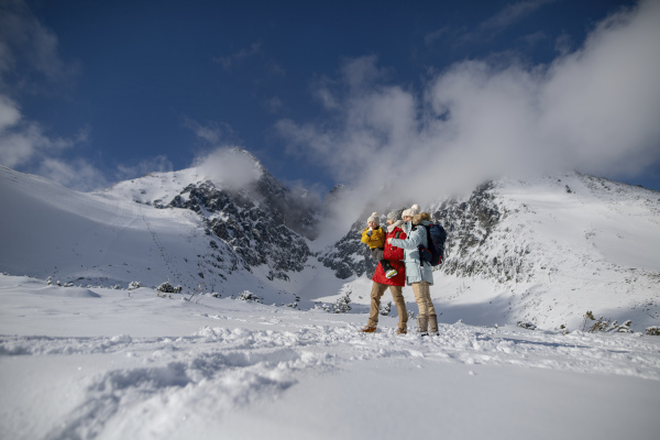 Family is enjoying winter holiday in the mountains, playing and walking through the snowy landscape.