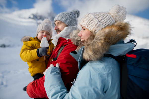 Family is enjoying winter holiday in the mountains, standing in the middle of snowy landscape.