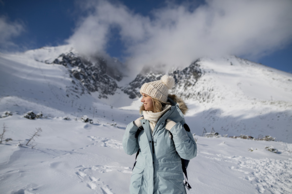 Woman standing in the middle of the snowy nature looking at the winter landscape around her.