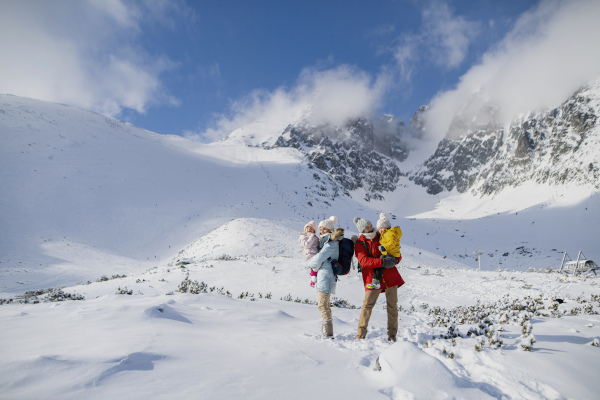 Family is enjoying winter holiday in the mountains, standing in the middle of snowy landscape.