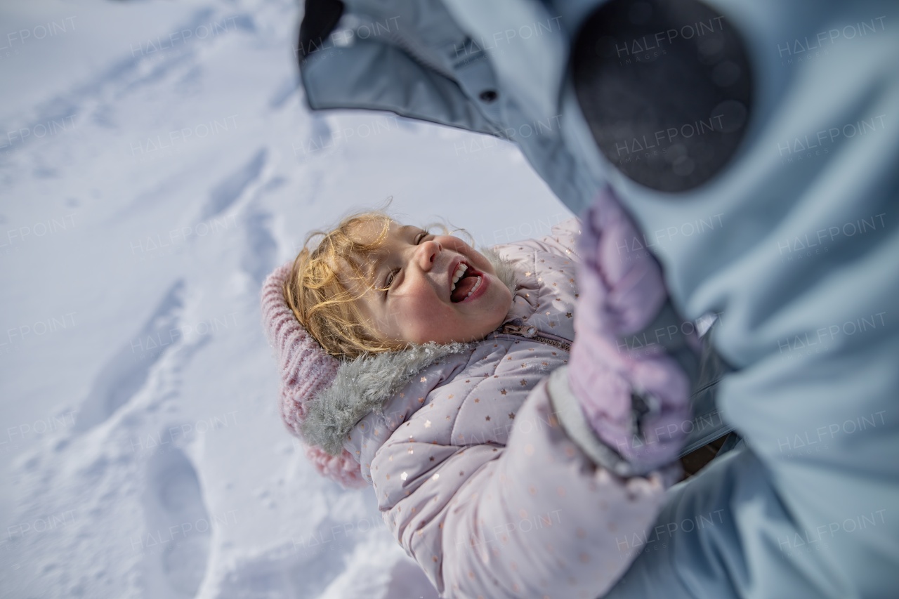 Mom playing with small girl. Family enjoying winter holiday in the mountains, playing in snow