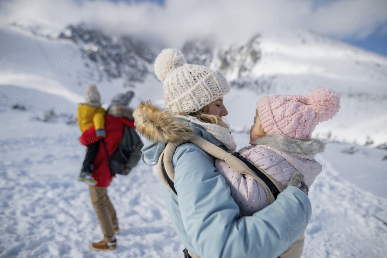 Family is enjoying winter holiday in the mountains, standing in the middle of snowy landscape.