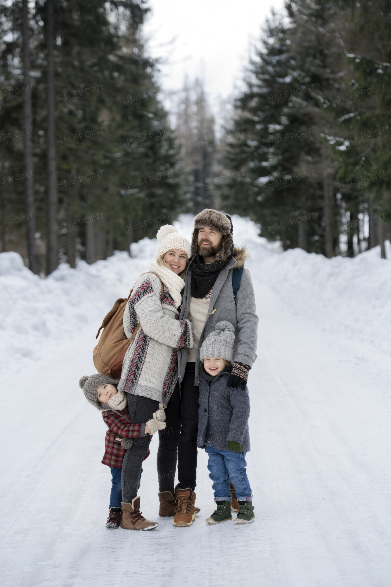 Portrait of family standing in the middle of winter snowy nature. Winter holiday in the mountains.