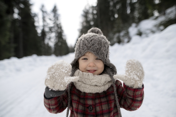 Portrait of a small girl enjoying winter holiday in the mountains with family, playing in snow.