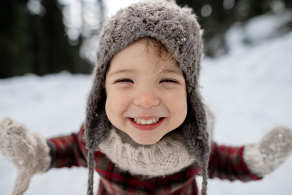 Portrait of a small girl enjoying winter holiday in the mountains with family, playing in snow.