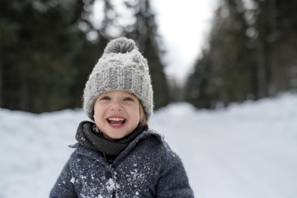 Portrait of a small boy enjoying winter holiday in the mountains with family, playing in snow.