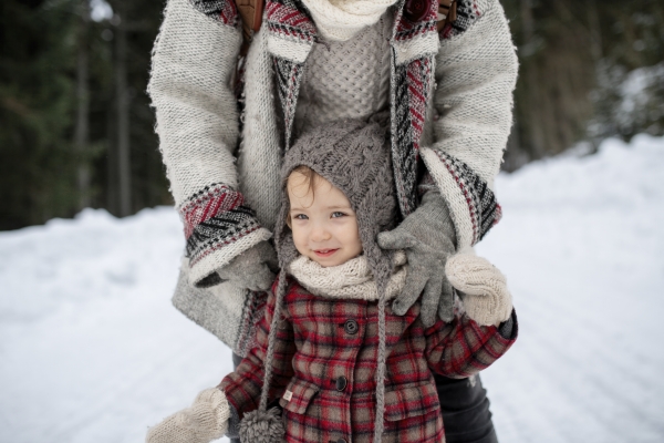 Mother and daughter standing in the middle of snowy landscape. Mom and girl enjoying winter holiday in mountains.