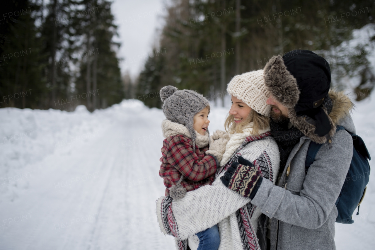 Family is enjoying winter holiday in the mountains, standing in the middle of snowy forest.