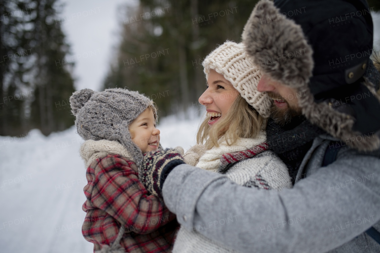 Family is enjoying winter holiday in the mountains, standing in the middle of snowy forest.