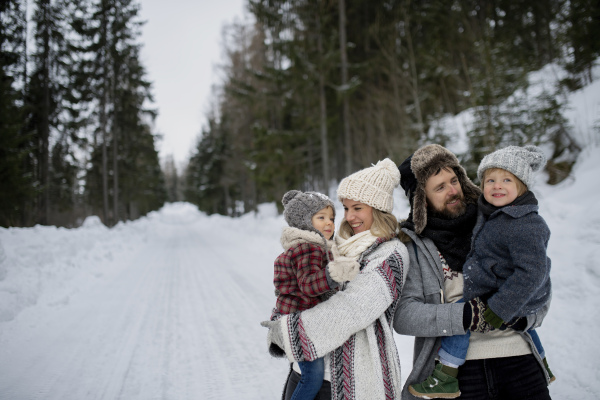 Family is enjoying winter holiday in the mountains, standing in the middle of snowy forest.