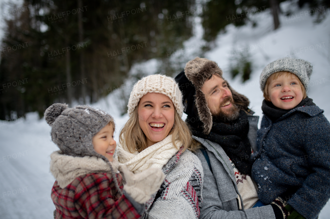 Family is enjoying winter holiday in the mountains, standing in the middle of snowy forest.