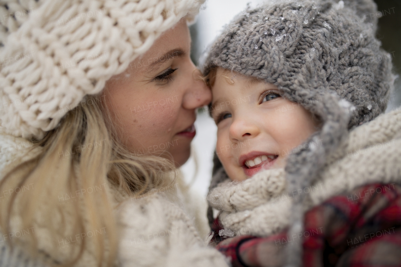 Potrait of mother in the middle of snowy landscape holding daughter in arms. Mom and girl enjoying winter holiday in the mountains