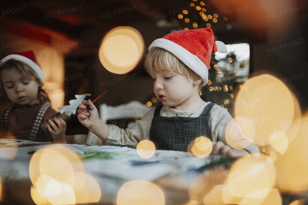 Siblings making holiday Christmas cards for family. Children painting pictures for Santa Claus, making christmas decorations with tempera paints.