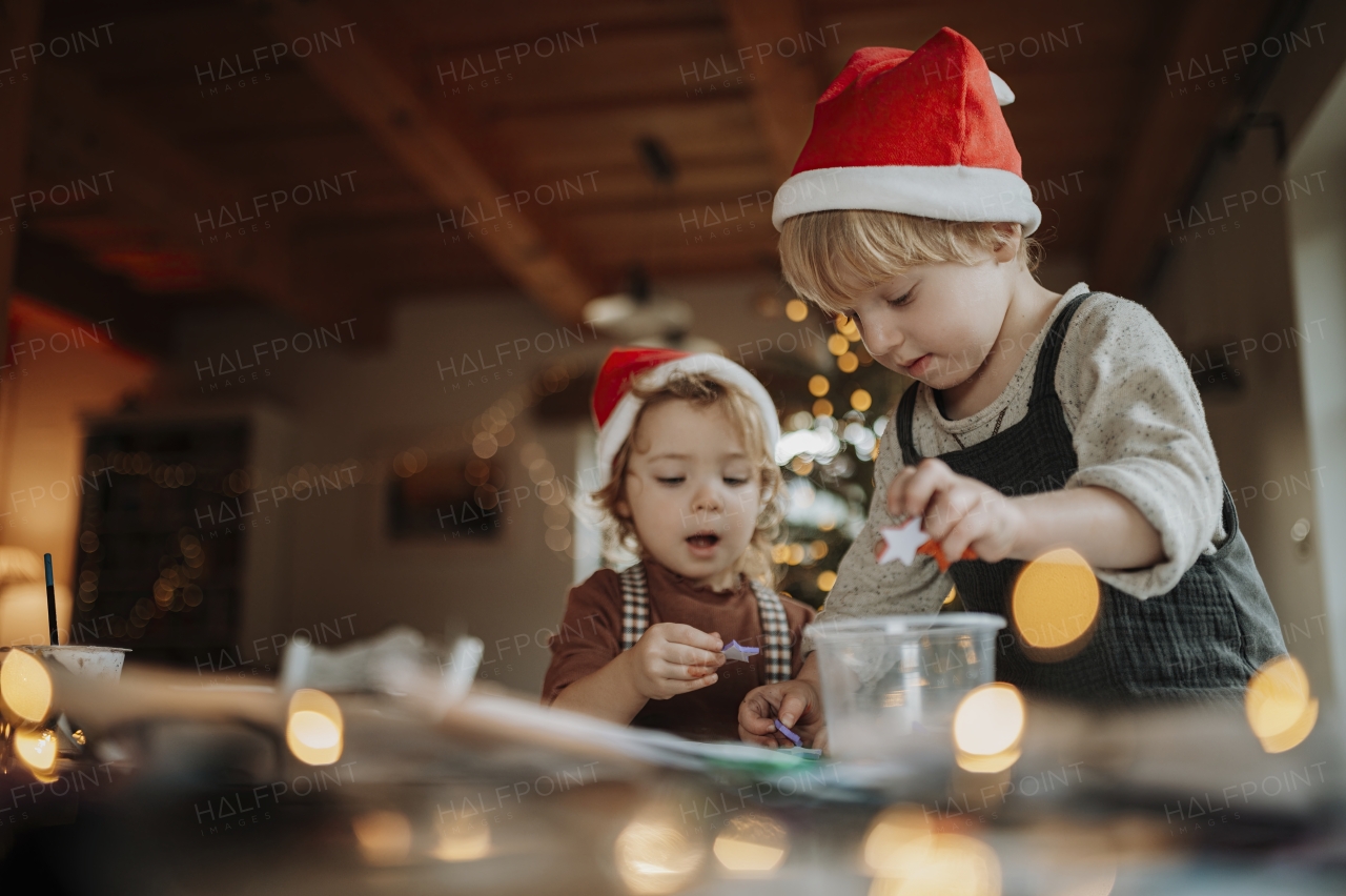 Siblings making holiday Christmas cards for family. Children painting pictures for Santa Claus, making christmas decorations with tempera paints.