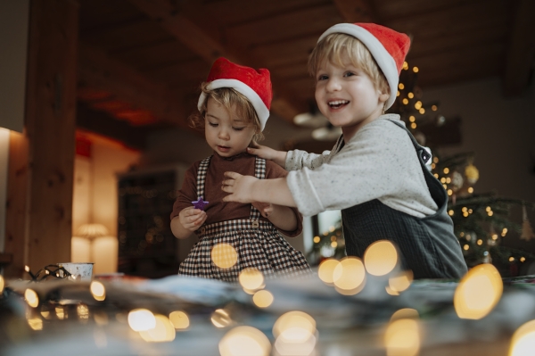 Siblings making holiday Christmas cards for family. Children painting pictures for Santa Claus, making christmas decorations with tempera paints.