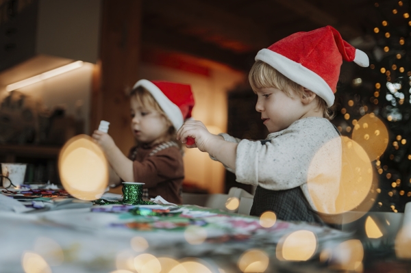 Siblings making holiday Christmas cards for family. Children painting pictures for Santa Claus, making christmas decorations with tempera paints.