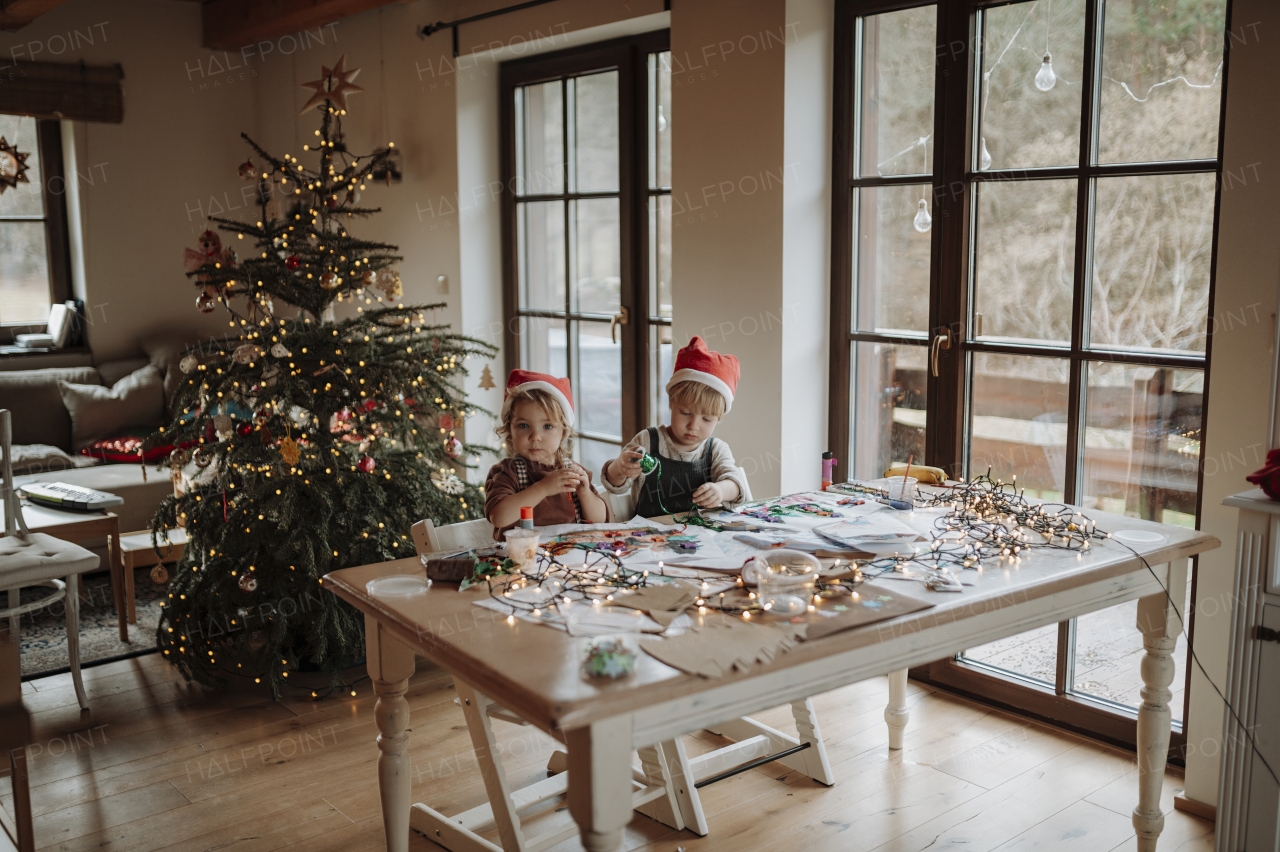 Siblings making holiday Christmas or a christmas decorations at home. Creative activity for toddlers.