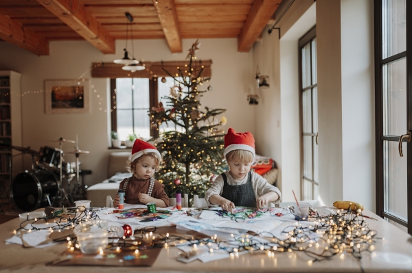 Siblings making holiday Christmas or a christmas decorations at home. Creative activity for toddlers.