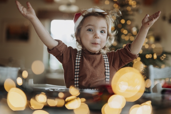 Portrait of small girl helping with Christmas baking at home, laughing. Girl making christmas cookies in the kitchen.