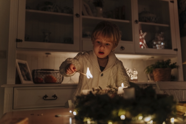 Little boy lighting candles on advent wreath. Christian tradition.