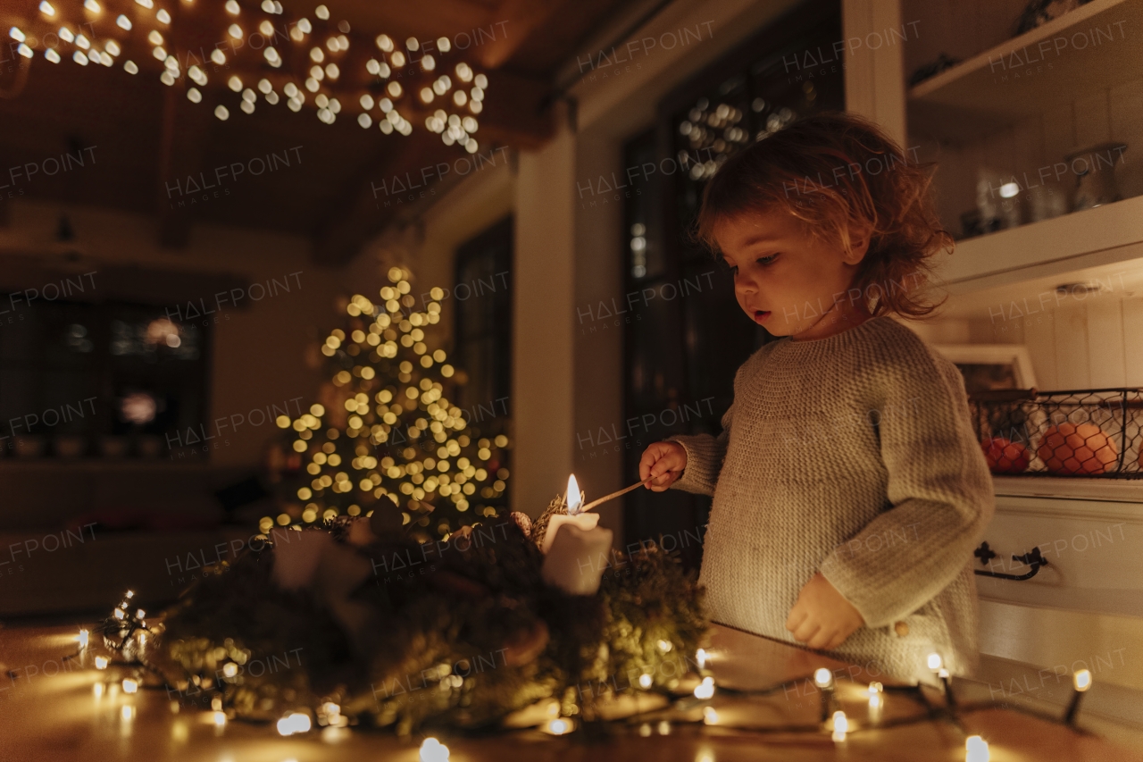 Little girl lighting candles on advent wreath. Christian tradition.