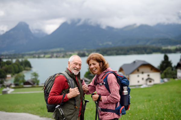 Active elderly couple hiking together in autumn mountains. Senior tourists enjoying nature and exercising.