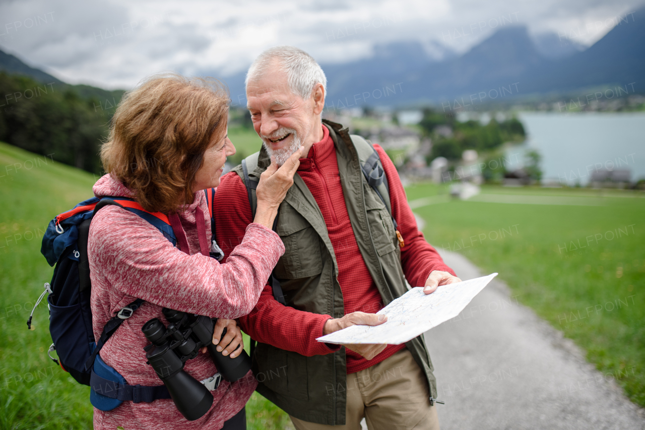 Active elderly couple hiking together in mountains, enjoying nature. Senior tourists looking at route on a map.