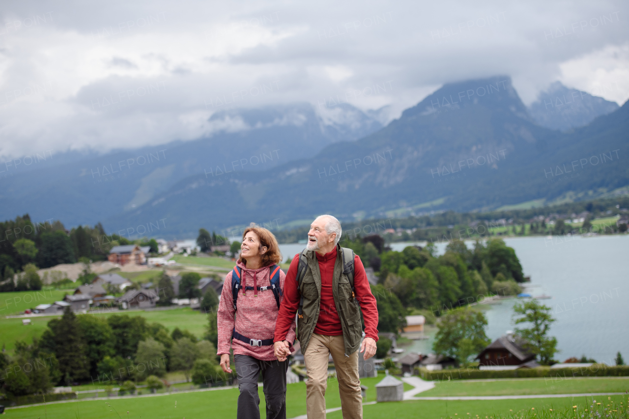 Active elderly couple on trip together, during early spring day. Senior tourists visiting, exploring new places. Sightseeing, holding hands.