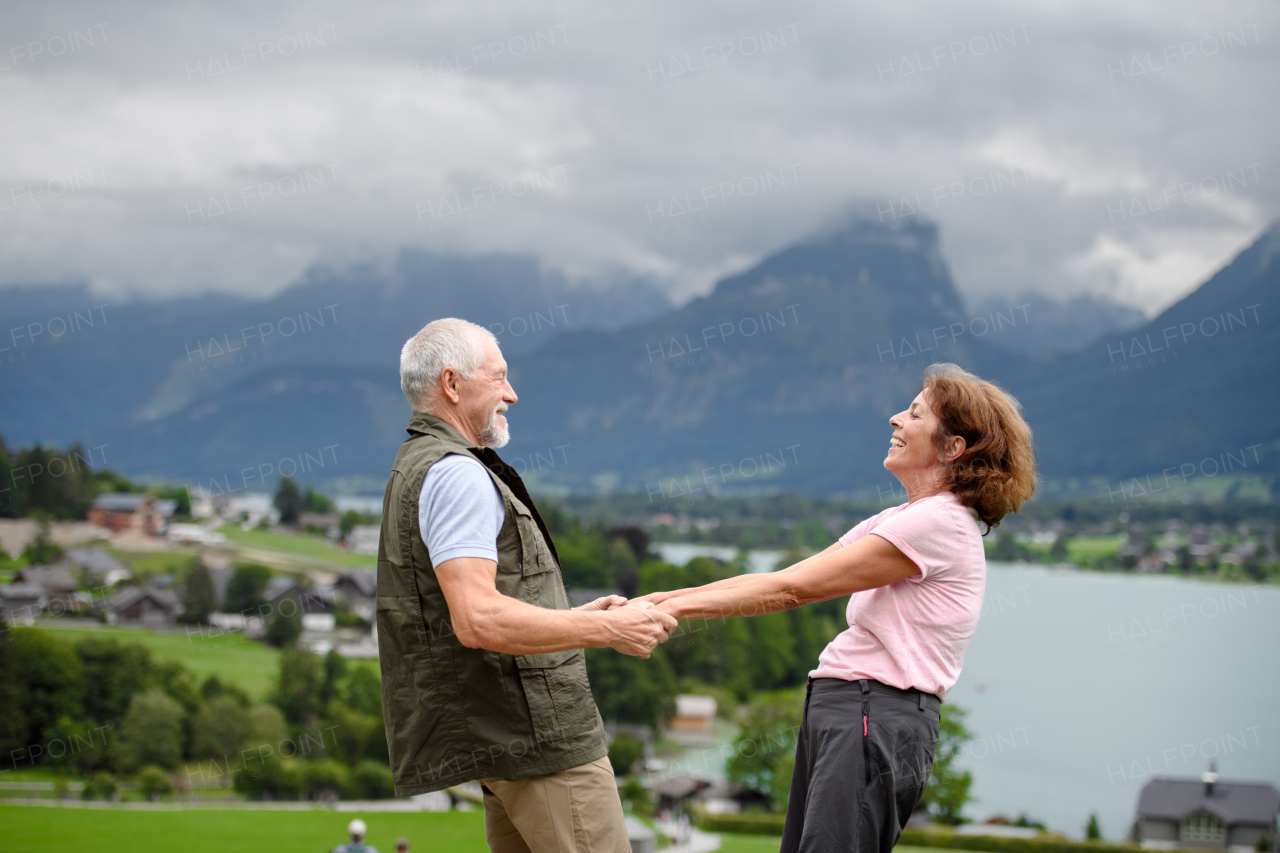 Active elderly couple on trip together, during early spring day. Senior tourists visiting, exploring new places. Side view, holding hands.